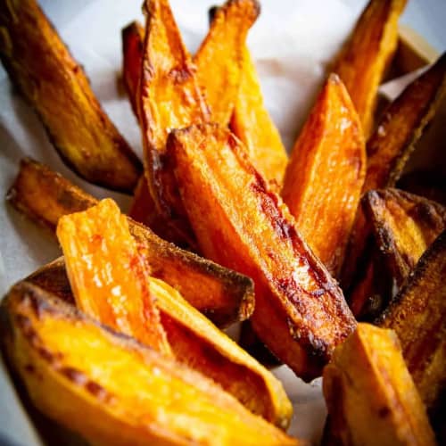 Bowl of sweet potato wedges with a dip in the front.