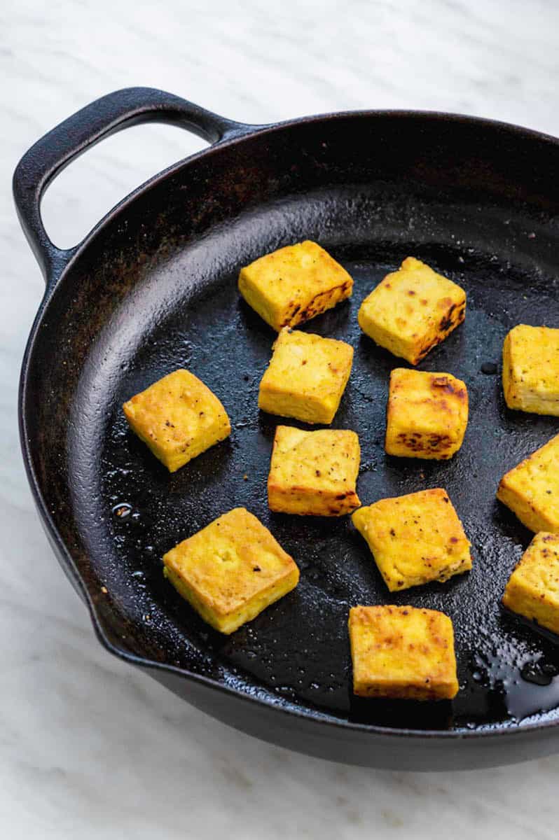 Frying tofu cubes in a cast-irons skillet.