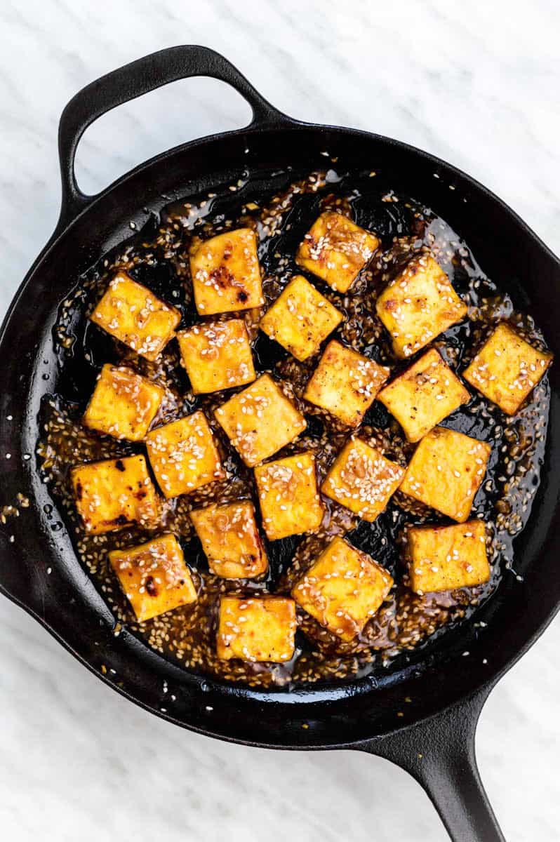 Cooking honey garlic tofu in a cast-iron skillet.