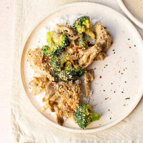 peanut butter stir fry on a white plate on a kitchen towel.