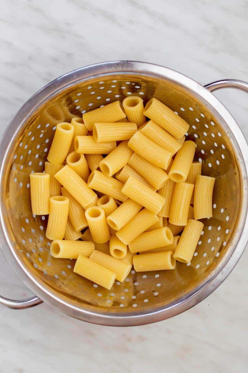 Cooked rigatoni pasta in a stainless-steel colander.