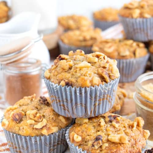 two vegan banana muffins with one on top of them and some more in the background.