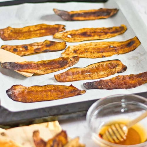 eggplant bacon slices on parchment paper on a baking sheet.
