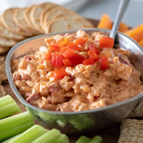 Bowl of vegan pimento cheese topped with diced pimentos.