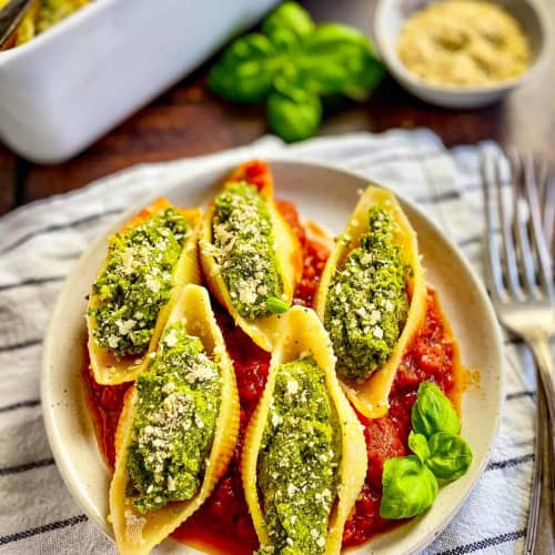 Stuffed shells on a plate with tomato sauce underneath.