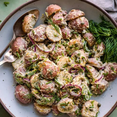 Bowl of potato salad with herbs on the table.