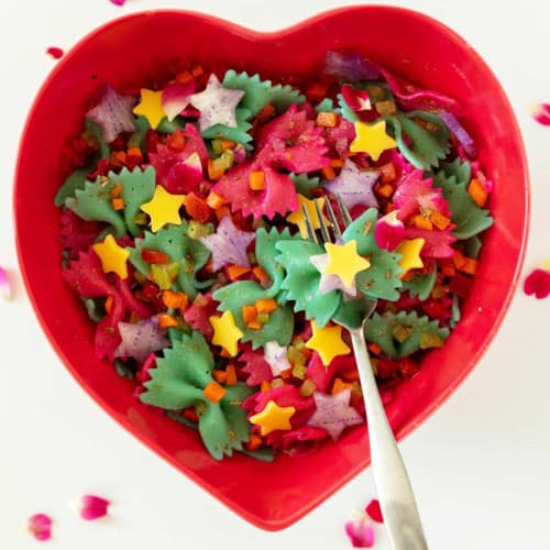 Heart shaped bowl with colorful bowtie pasta.