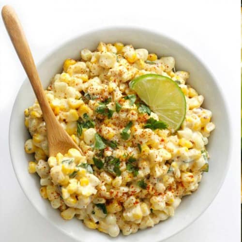 Bowl of corn salad with a wooden spoon in it.