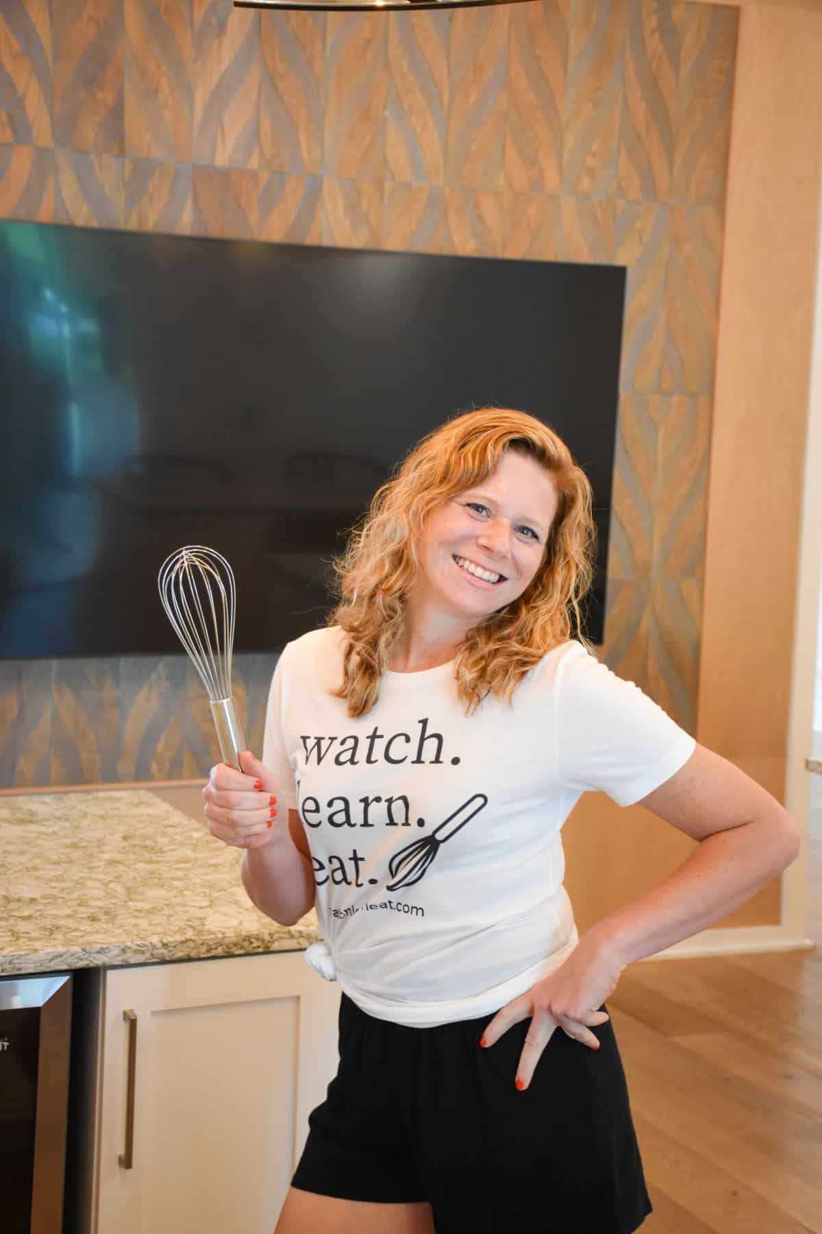 blog author standing in kitchen holding a whisk.