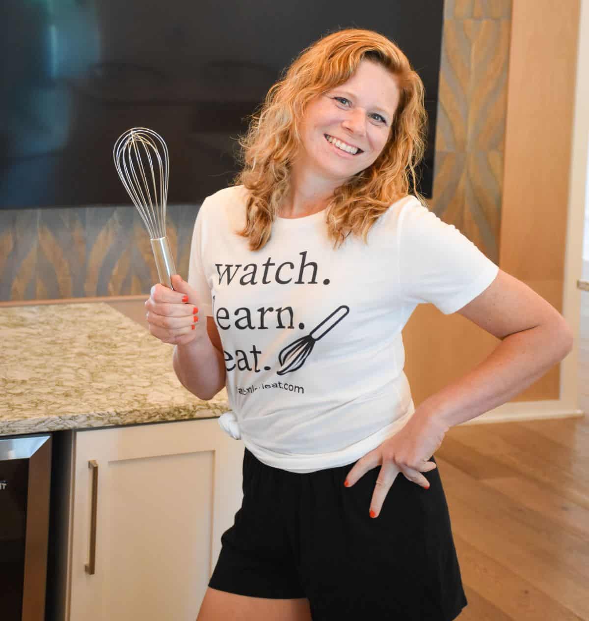 close-up of blog author standing in kitchen holding a whisk.
