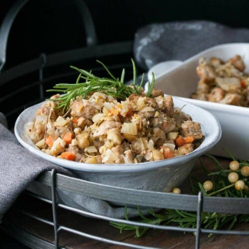 Vegan stuffing in a bowl topped with fresh rosemary.