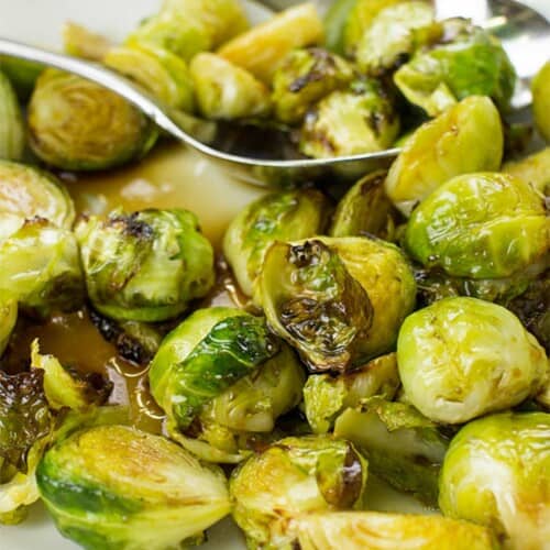 Brussels sprouts in a bowl with serving spoons.