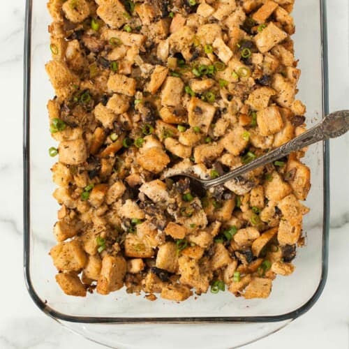 Bread stuffing in a casserole dish with a spoon.
