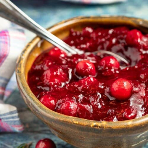 Cranberry sauce in a wooden bowl with a spoon.