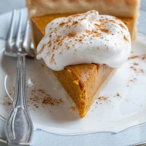 Slice of vegan pumpkin pie topped with whipped cream.