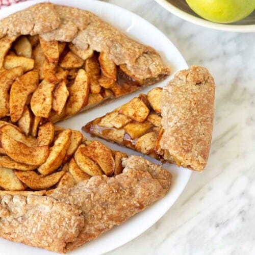 Apple galette on a plate with a slice cut out.