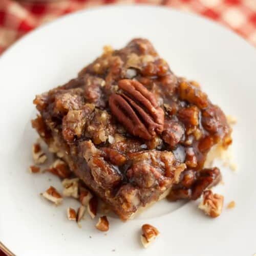 Pecan bar on a plate topped with pecan half.