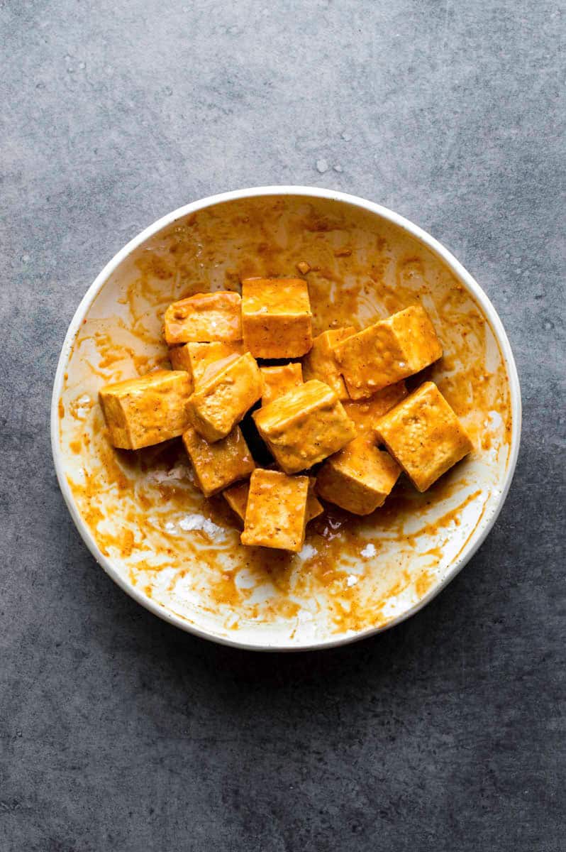 Marinated tofu cubes in a white bowl.
