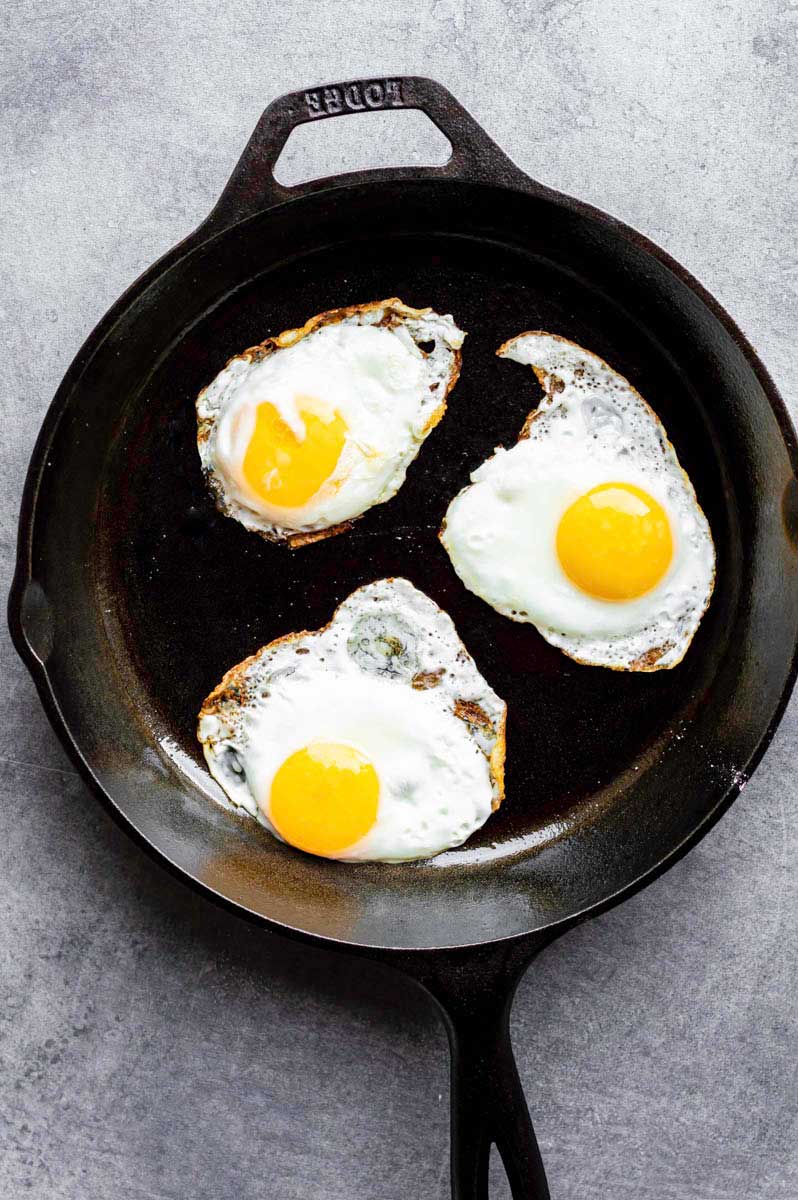 Frying sunny side up eggs in a cast-iron skillet.