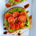 close-up of piece of tomato avocado toast on white plate.