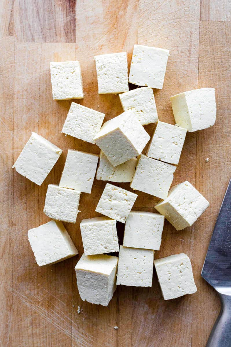 Overhead of diced tofu on a cutting board.