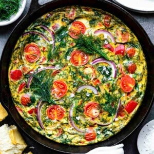 Dairy-free frittata in a cast-iron skillet topped with fresh dill and flaky sea salt.