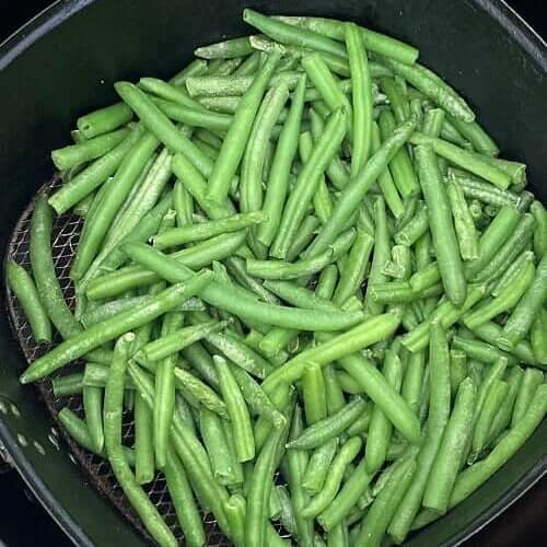 green beans in air fryer basket after cooking.