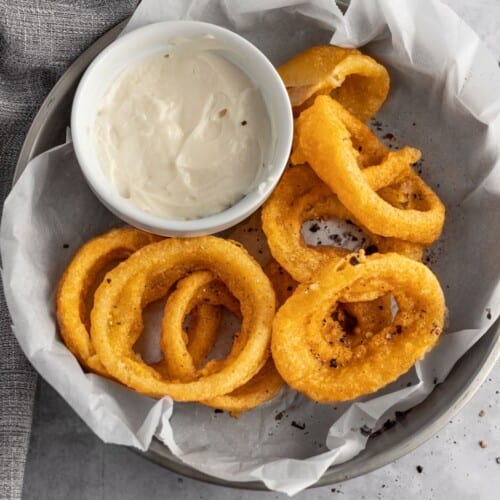 overhead of onion rings with side of dipping sauce.