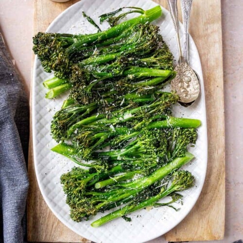 overhead of broccolini on a white serving platter.