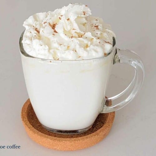 white coffee drink in a clear mug with cream on top.