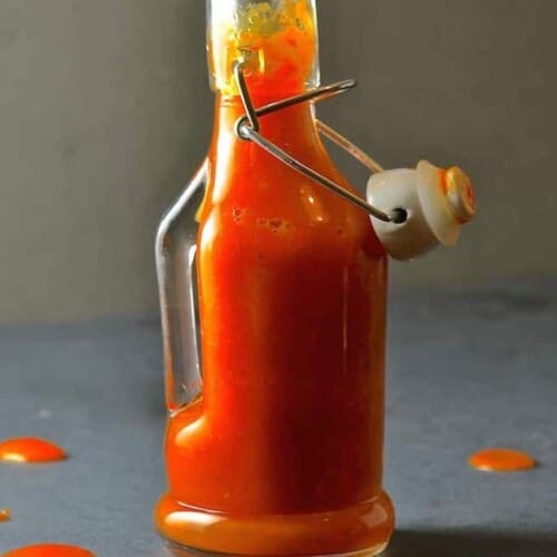 botella de salsa picante casera abierta con algunas salpicaduras.