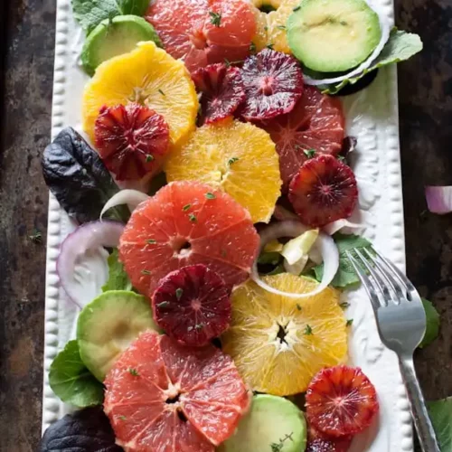 overhead of citrus salad on a white serving dish with a fork.