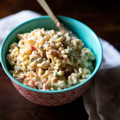 macaroni salad in a bowl with a spoon in it.