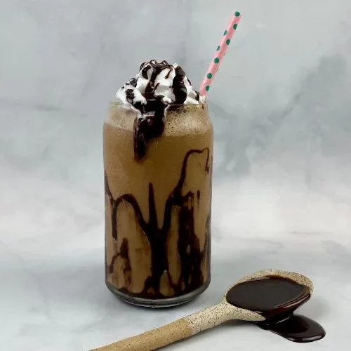 frappuccino in a glass with whipped cream and a straw.