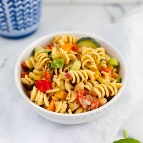 vegan pasta salad in a white bowl on a white kitchen towel.