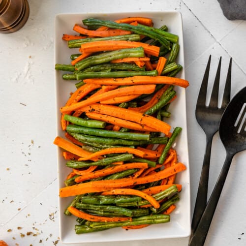 overhead of carrots and green beans on white serving platter.