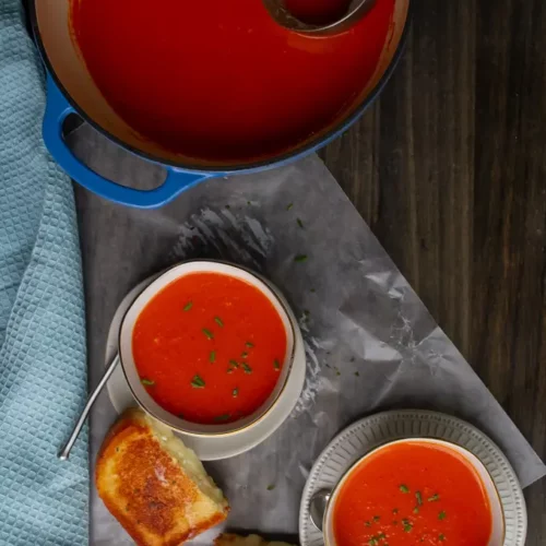 overhead of tomato soup from canned tomatoes in a white bowl with grilled cheese sandwich.
