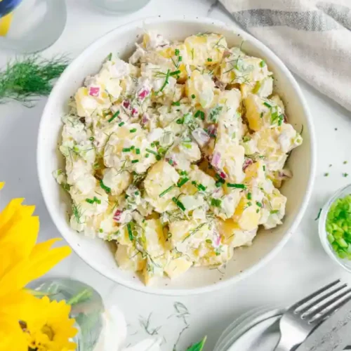 overhead of vegan potato salad with dill in a white bowl.