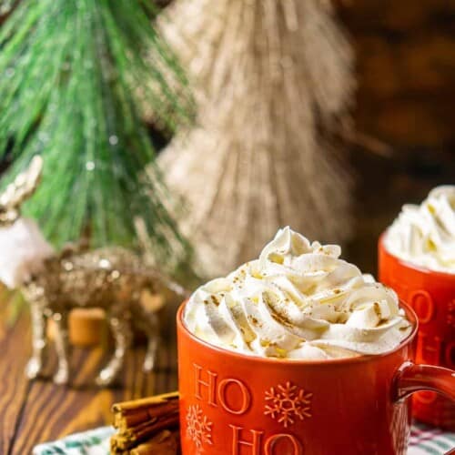 latte in a brown mug with whipped cream on top.
