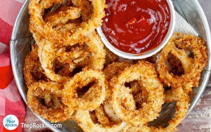 overhead of homemade onion rings on a dish with ketchup.
