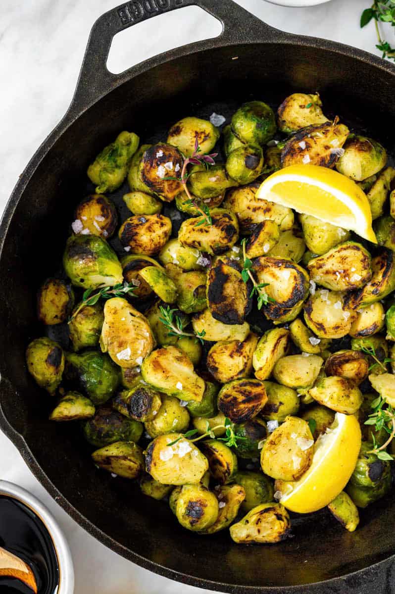 A close-up photo of browned brussels sprouts in a cast-iron skillet.