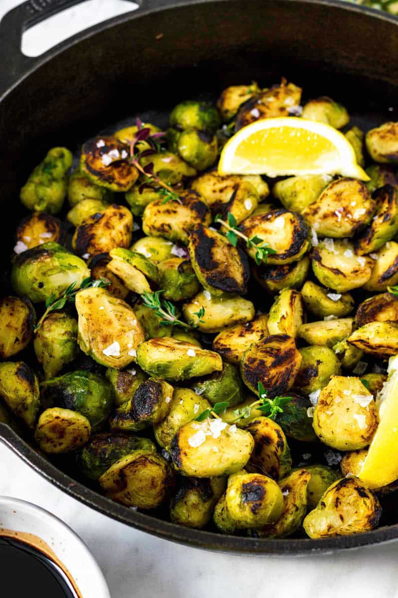 A cast iron skillet filled with cooked frozen brussels sprouts that are topped with sea salt.