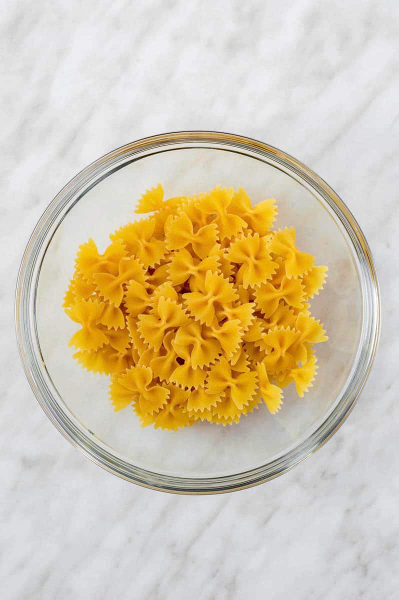 Dry farfalle pasta in a microwave-safe bowl.