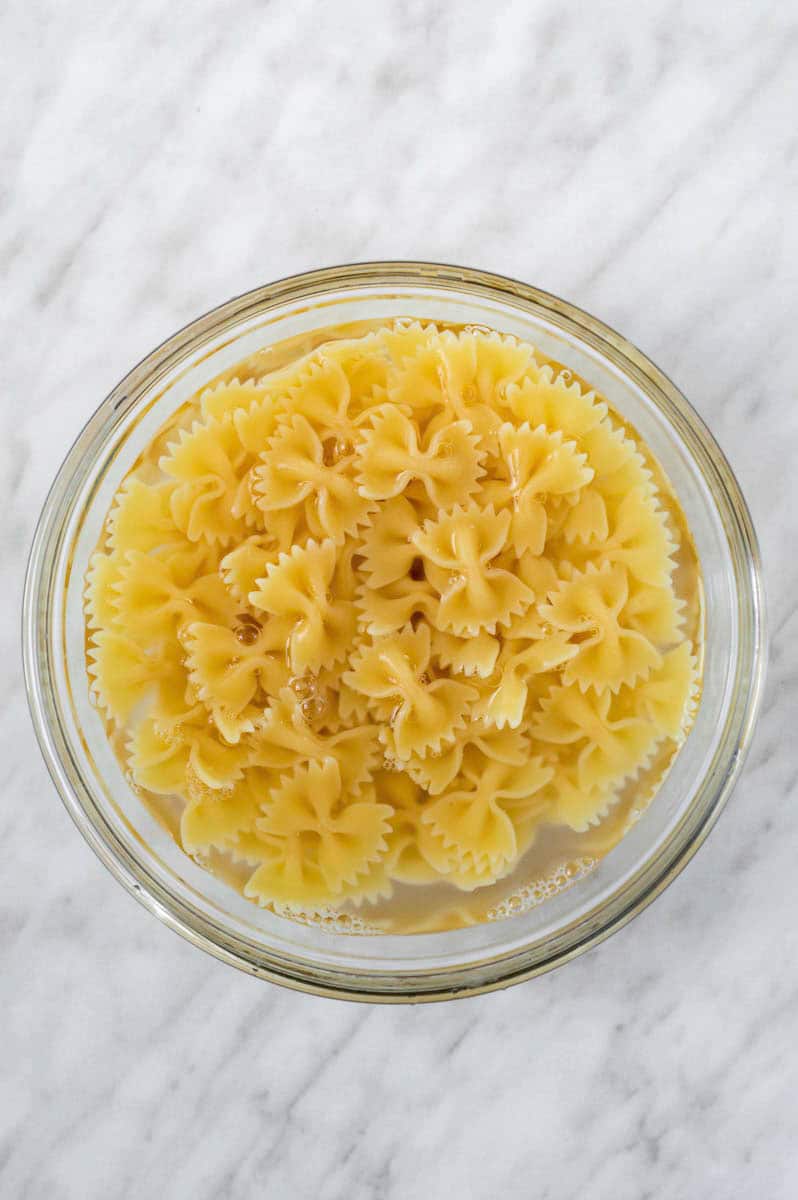 Microwaved farfalle pasta in a mixing bowl with pasta water.