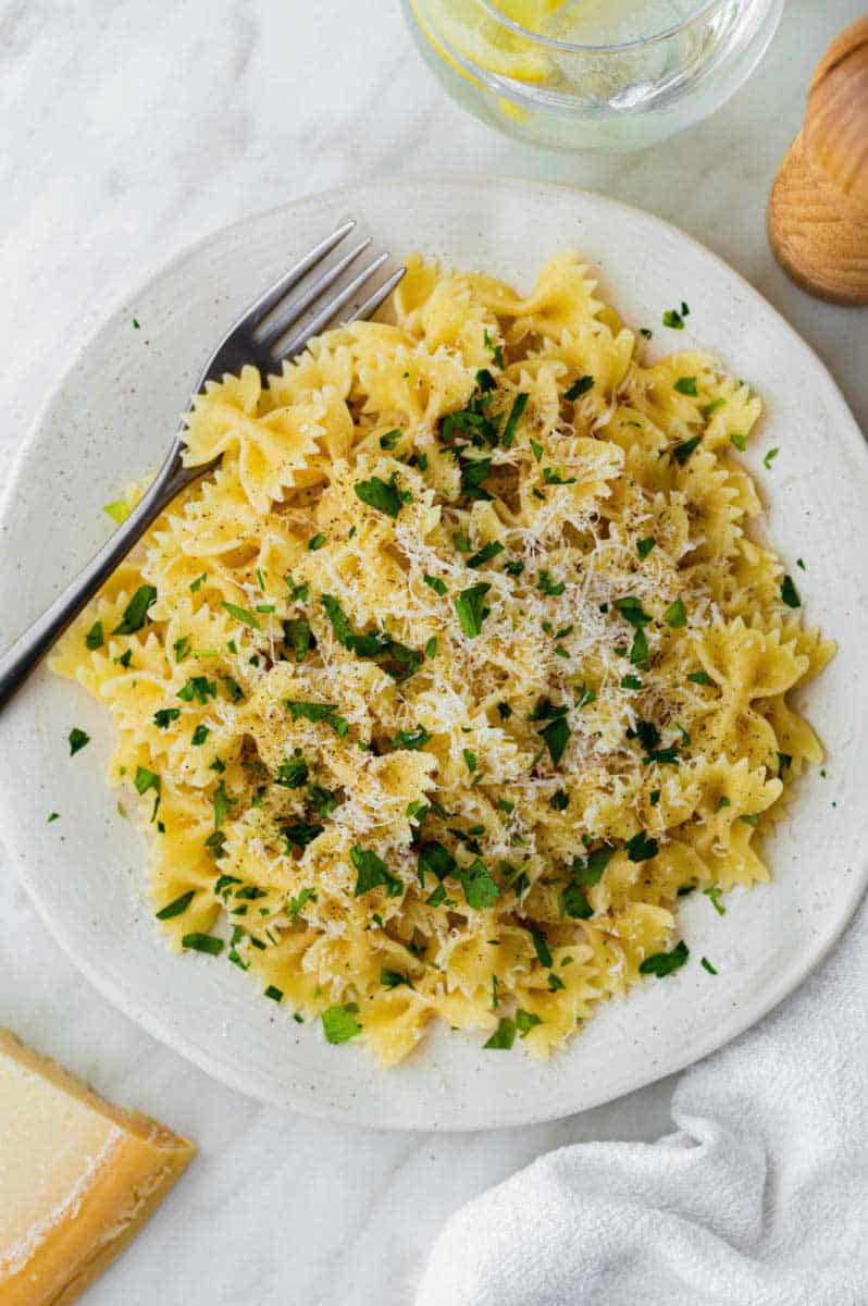 Microwave cooked pasta served on a white plate and topped with grated parmesan cheese and chopped parsley.