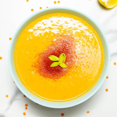 overhead of red lentil soup on a white bowl.