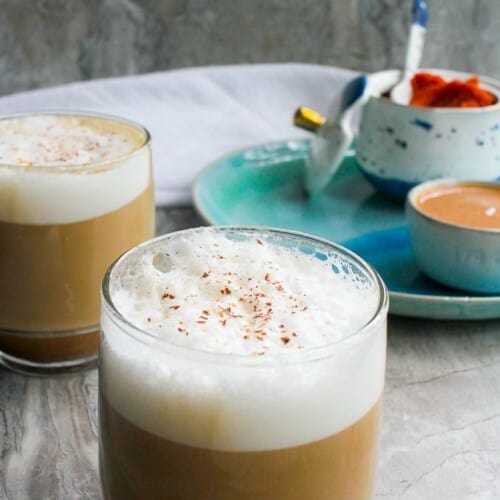 latte in a glass mug with spice on top.