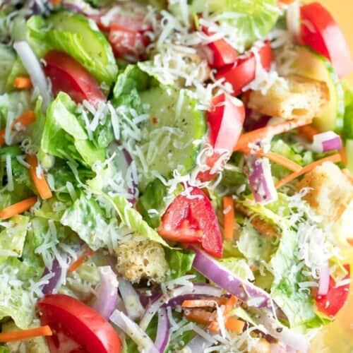 close-up of side salad with colorful veggies and Parmesan cheese.