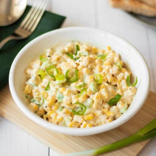 vegan corn salad in a white bowl on a wooden board.