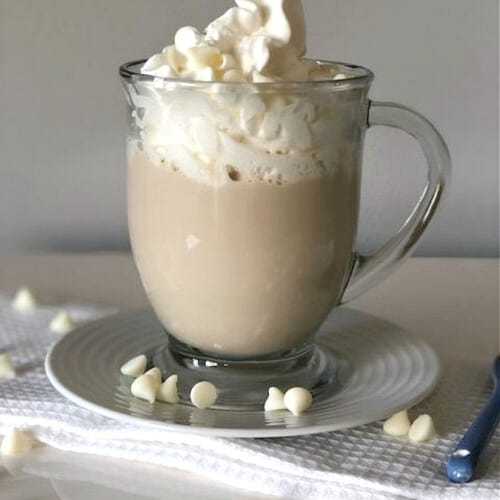 mocha drink in a glass mug with cream on top.